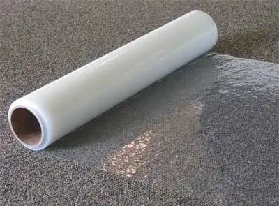 Contractor applying Presto carpet film by hand during surface protection setup

