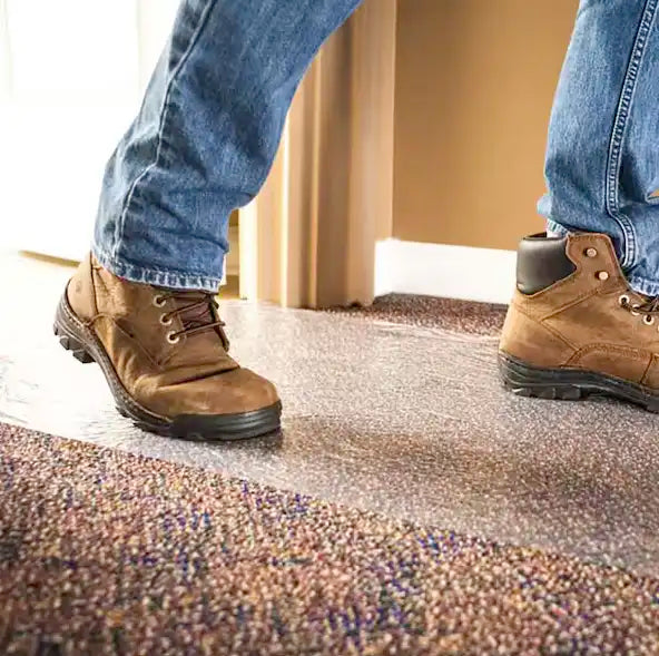 Clear carpet protection film laid flat across synthetic flooring in a home renovation site
