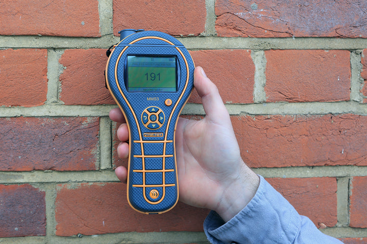 protimeter mms3 performing non-invasive moisture test on brick wall
