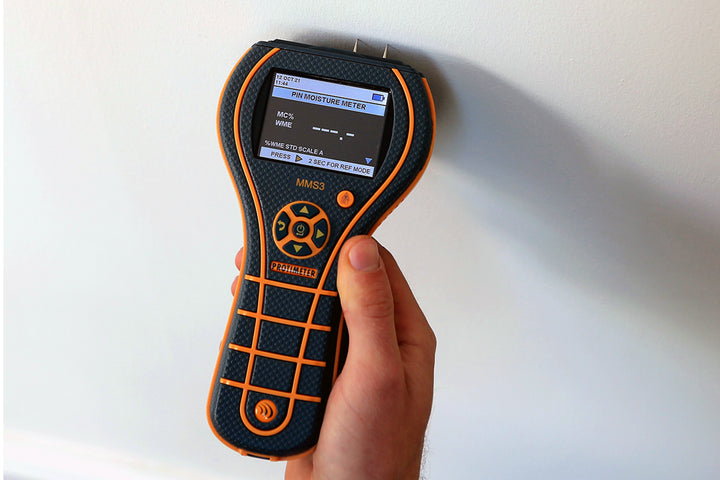 technician using protimeter mms3 to test wall moisture content with pin sensors
