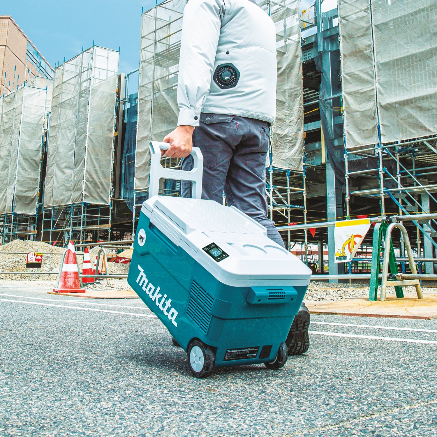 person pulling makita cooler warmer box with extended handle at outdoor location

