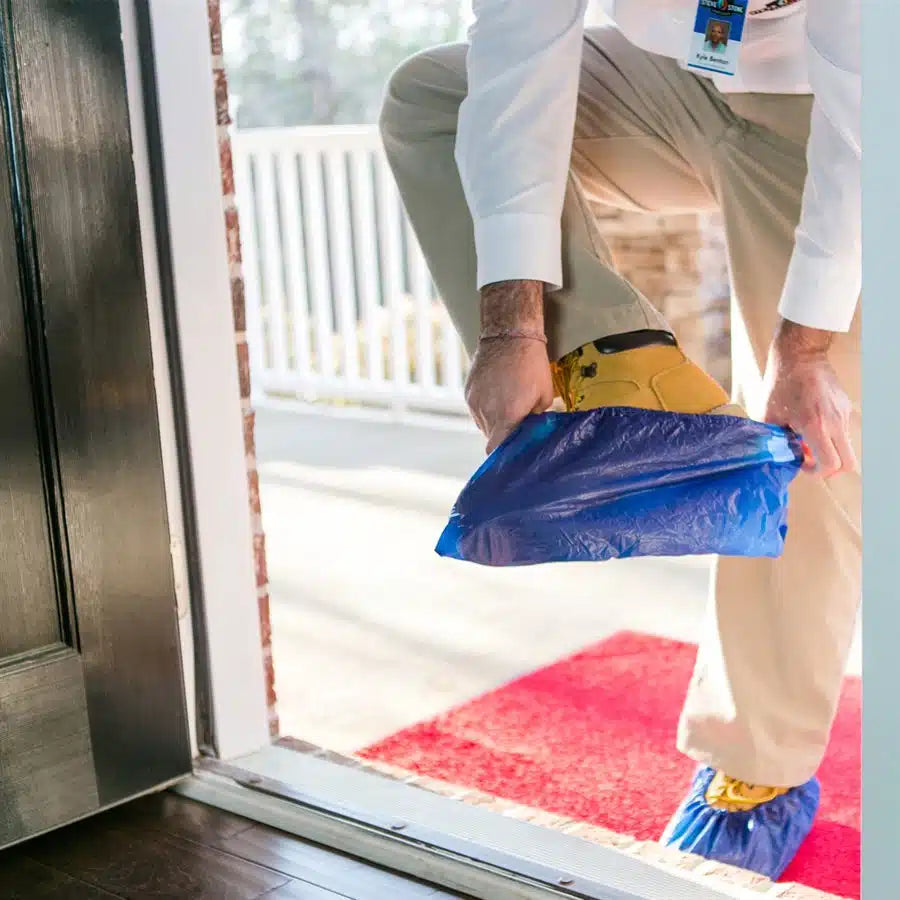 Contractor putting on Shubee waterproof shoe covers in doorway before entry
