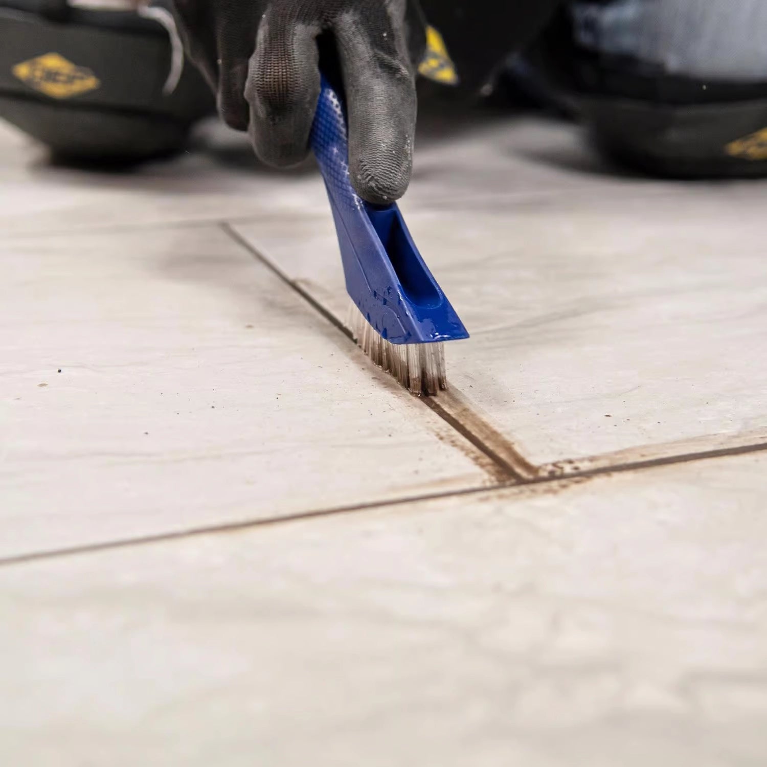 Alternate view of QEP Grout Cleaning Brush scraping grime from tile surface
