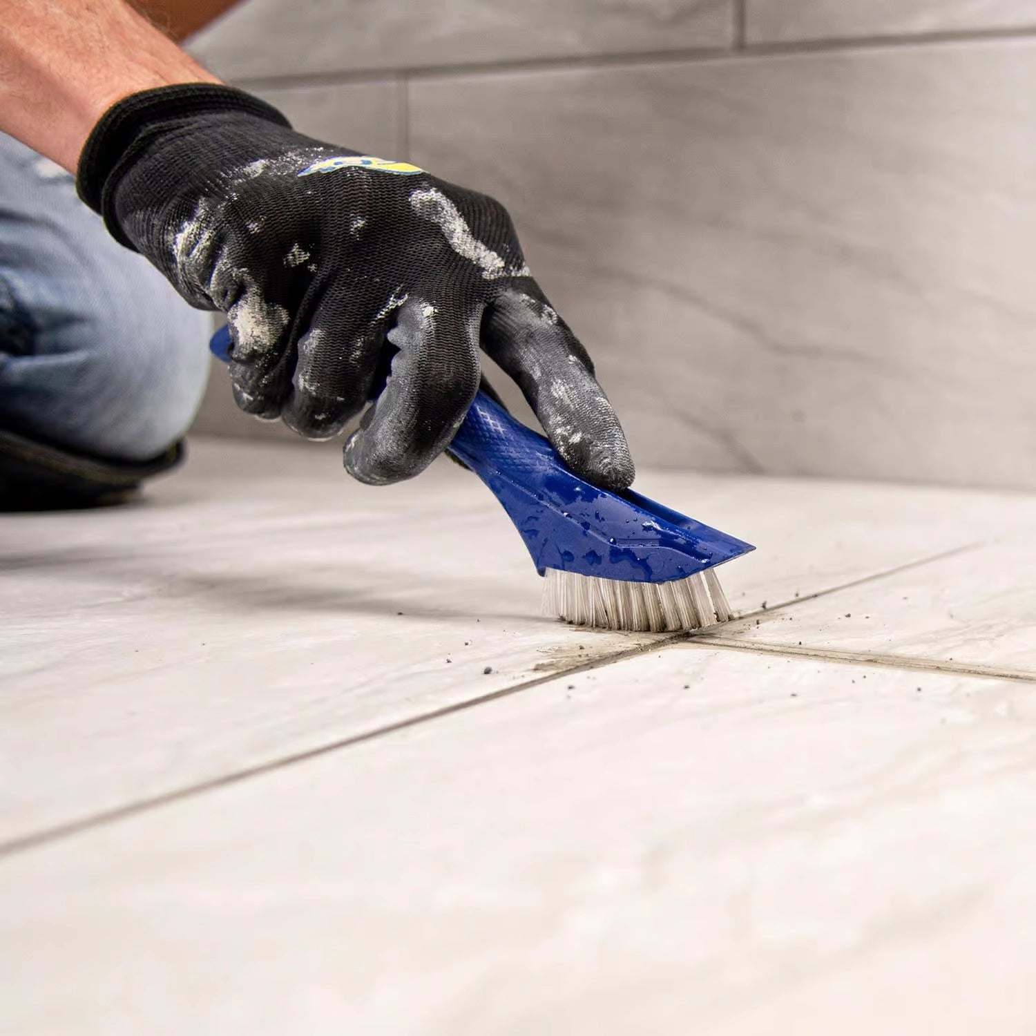 QEP brush scraping tile edge to remove grime with built-in scraper
