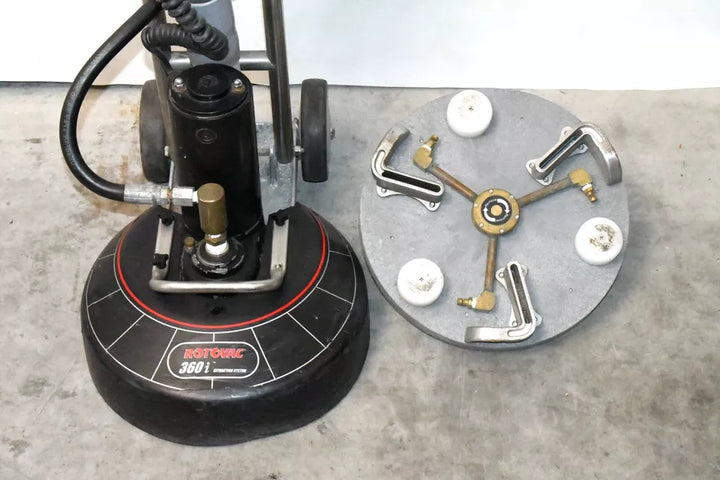 Rotovac 360i next to a detached 3-jet rotary cleaning head on concrete floor