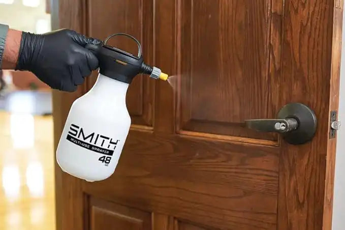 Technician using Smith Multi-Use sprayer to disinfect a door knob during restoration cleaning
