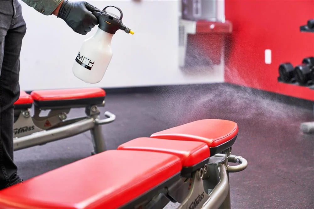 Smith chemical sprayer being used to sanitize gym equipment in a commercial fitness facility
