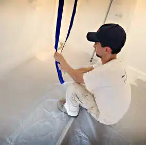 Restoration technician sealing heavy-duty zipper on plastic containment barrier
