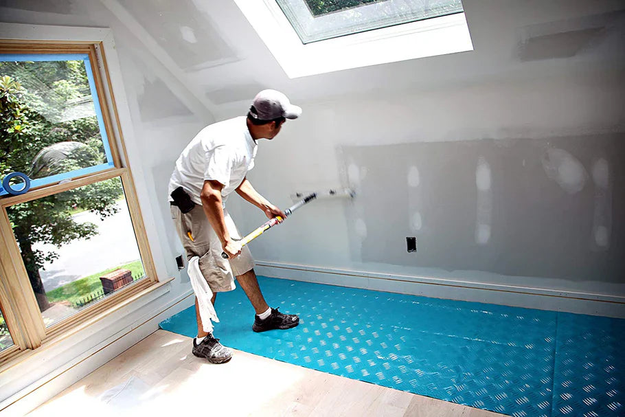 Contractor painting interior walls with Trimaco AquaShield surface protector installed on floor
