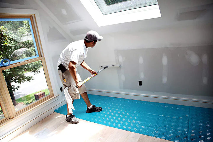 Contractor painting interior walls with Trimaco AquaShield surface protector installed on floor
