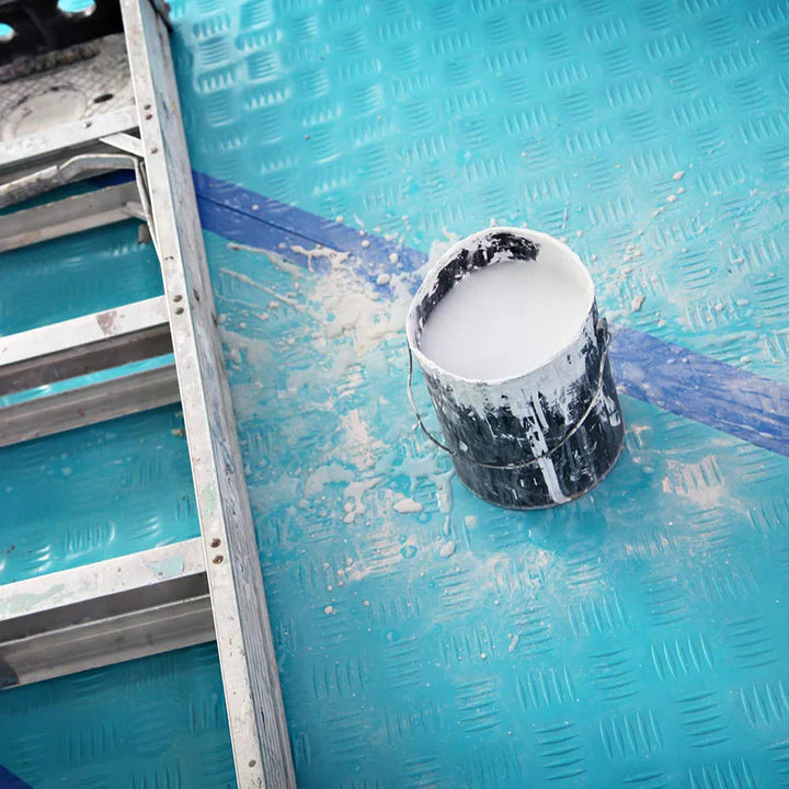 Paint spilled on Trimaco AquaShield film with clean floor underneath, showing waterproof protection
