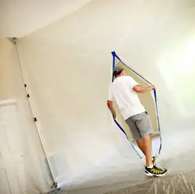 Worker walking through heavy-duty zipper access in plastic containment sheeting

