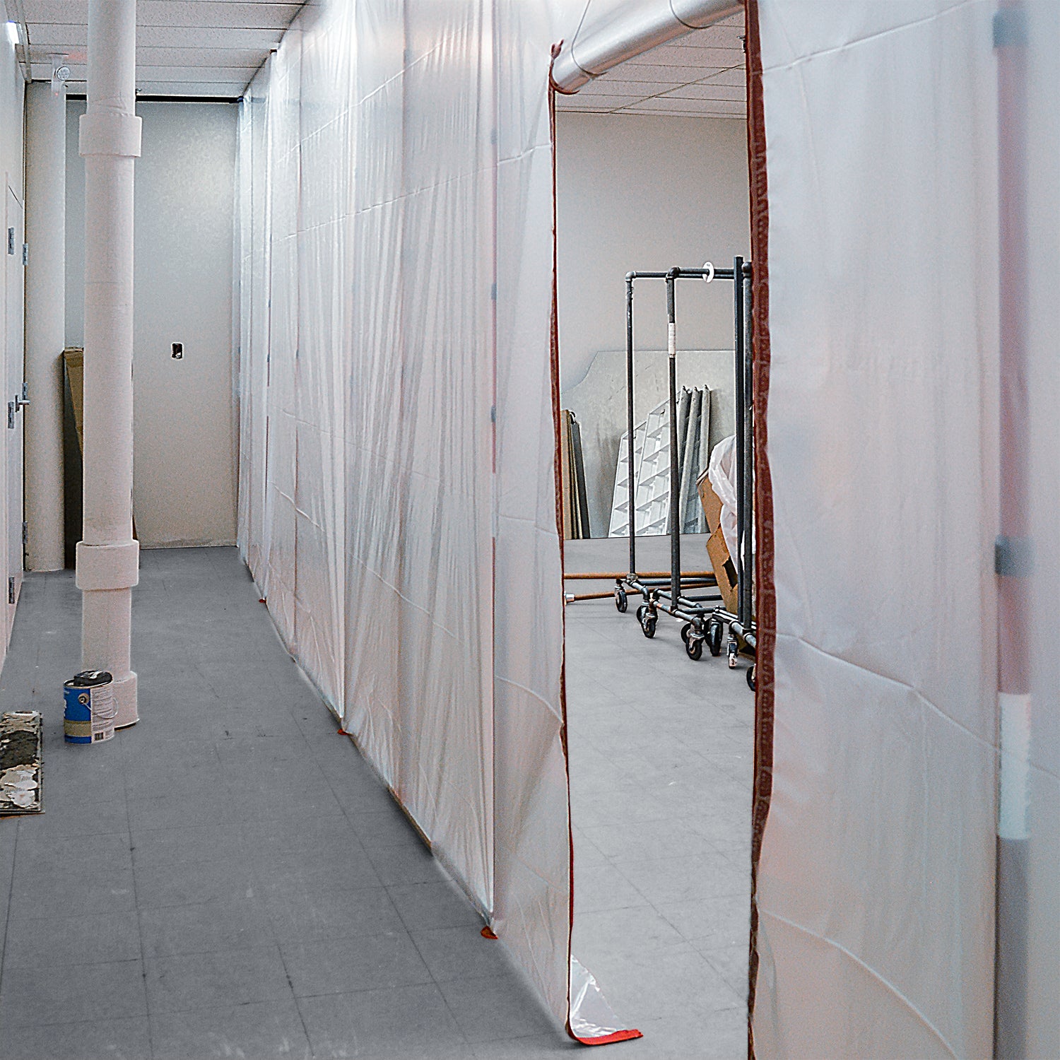 ZipWall tall containment poles used in building hallway with high ceilings

